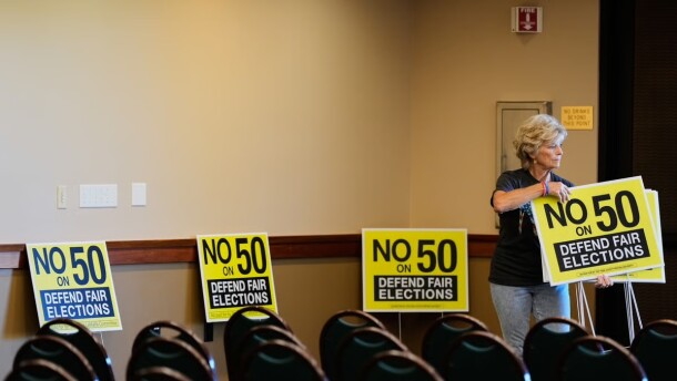Brenda Haynes places signs throughout a conference room before a No on Prop 50 rally in Redding, Calif., Tuesday, Oct. 21, 2025.