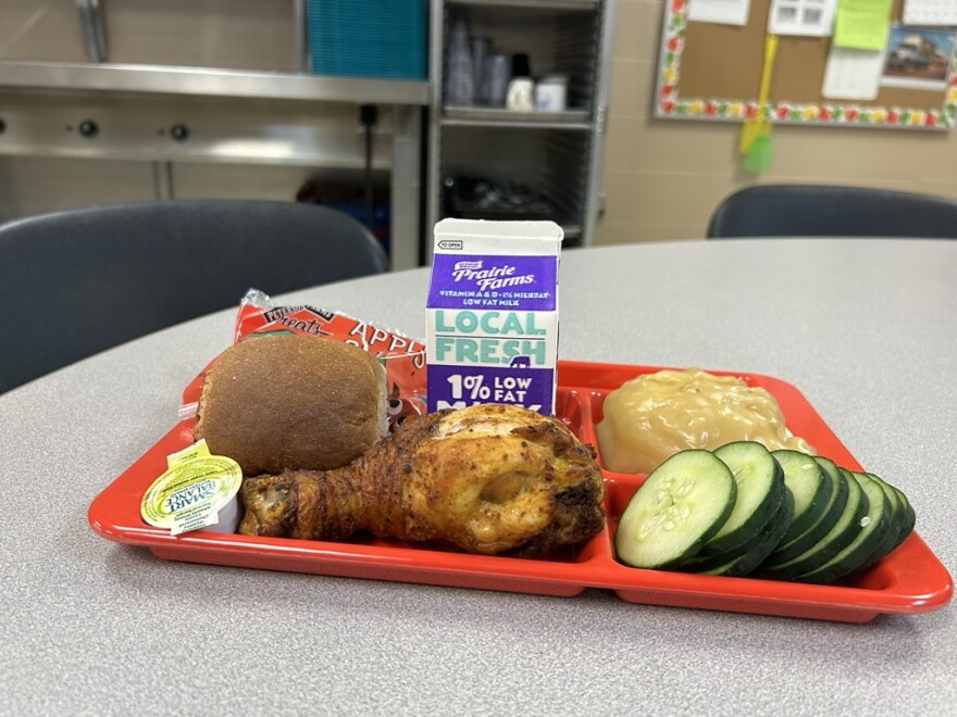 A tray with meat, veggies, potatoes and a small carton of milk. 