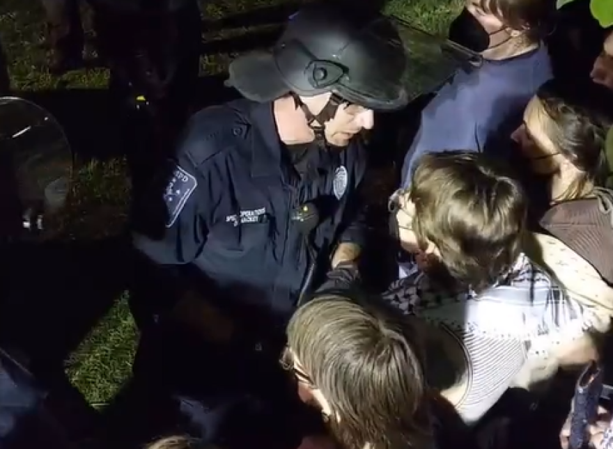 Officers approaching and detaining a group of students chanting "Hold the line" during an overnight protest at the University of Massachusetts, Amherst.