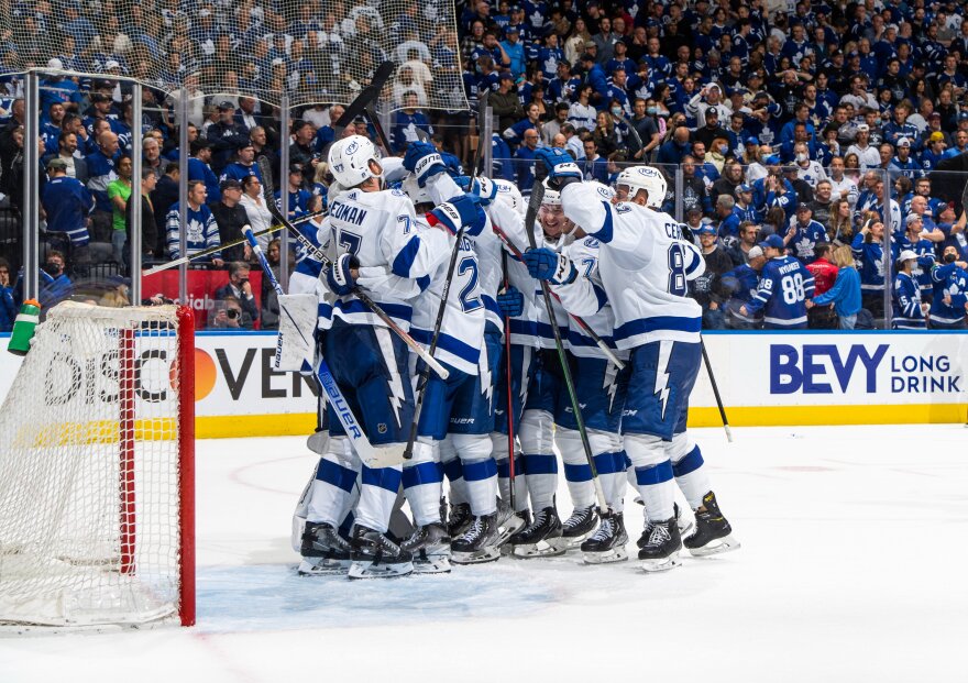 Lightning players cluster together on the ice to celebrate