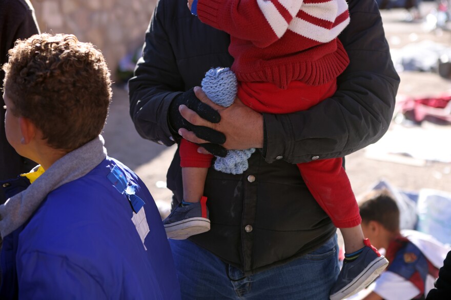 An asylum-seeking migrant from Venezuela holds one of his for sons as he is living unsheltered with his wife after crossing the Rio Grande River into the United States in El Paso, Texas, U.S., December 22, 2022.