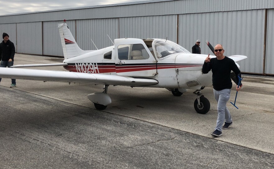 Jackson Busenbark carries a tow bar after towing his plane out of the aircraft hangar in preparation for a flight.