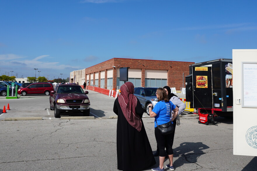 People stand by food trucks in the International Mall parking lot neighboring the Franklin County Board of Elections on Morse Road.