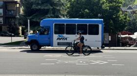 A RFTA bus is parked near the Rubey Park Transit Center in downtown Aspen, as a cyclist makes their way by.