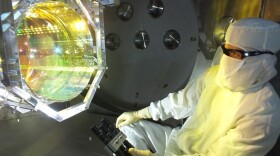 A LIGO optics technician inspects one of LIGO's core optics by illuminating its surface with light. It is critical to LIGO's operation that there is no contamination on any of its optical surfaces.