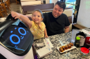 Four-year-old Emily Escalante, tickles the ears of Bella the cat robot, before eating dinner at Ninza Sushi East.