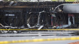 burned out building in a strip plaza with police tape in front of it.