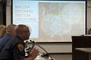 a police chief sits in the foreground, in the background a map shows locations for drone deployment docs in Bloomington
