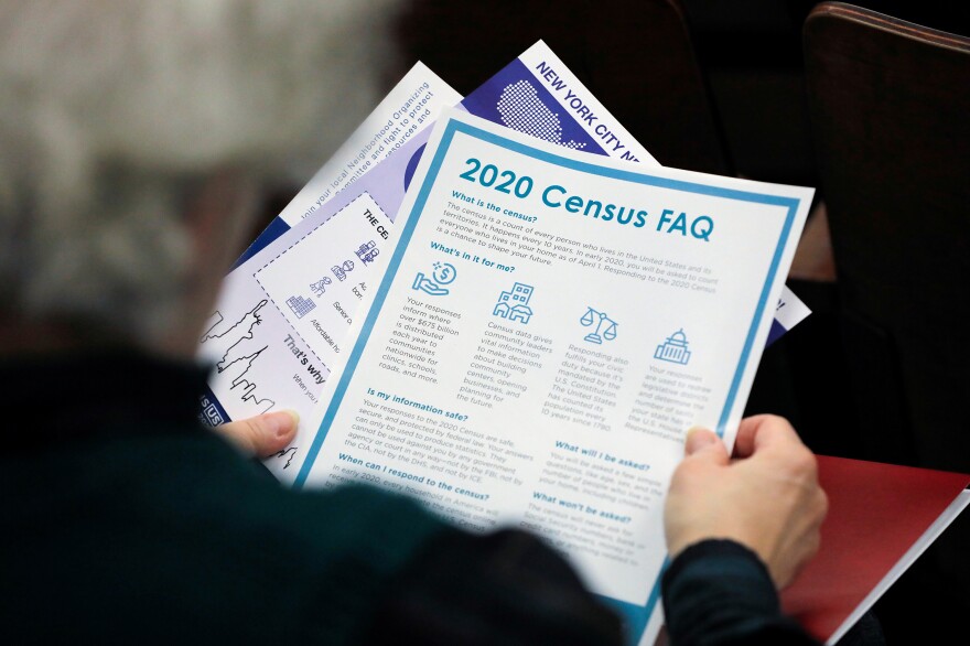 A person holds a flyer explaining the benefits of participating in the census during a 2020 town hall in East Elmhurst, N.Y.