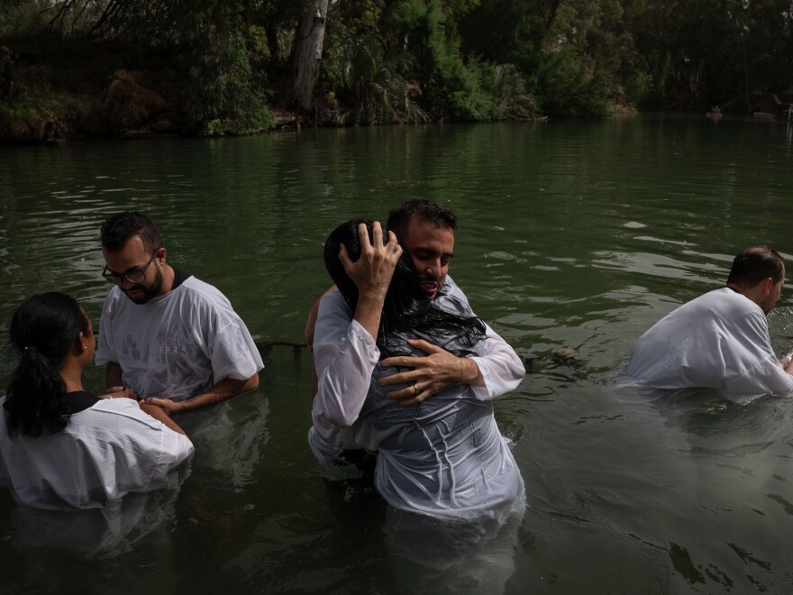 Evangelicals from Brazil wade, pray and get baptized in the Jordan river in Israel.