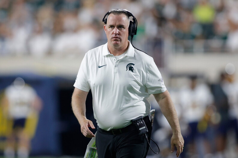 Michigan State head coach Pat Fitzgerald, wearing a white polo shirt and a communications headset, walks the sideline during a game on Sept. 4 in East Lansing, Mich.
