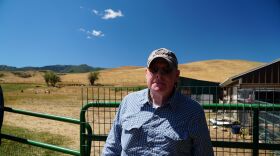 Dick Tennant at his Morgan farm with his goats grazing behind him.