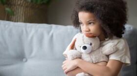 A photo of an upset little girl holding a teddy bear. 