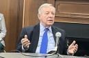 U.S. Senator Dick Durbin sitting at a round table with a microphone on it. His shirt is light blue. His tie is vibrant cerulean. 