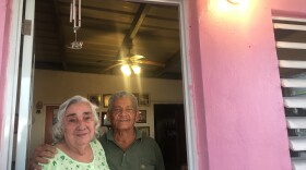 Rosa Cruz and Luis Felipe Colón standing beneath the newly illuminated light on their front porch. The couple had been without electricity for four months.