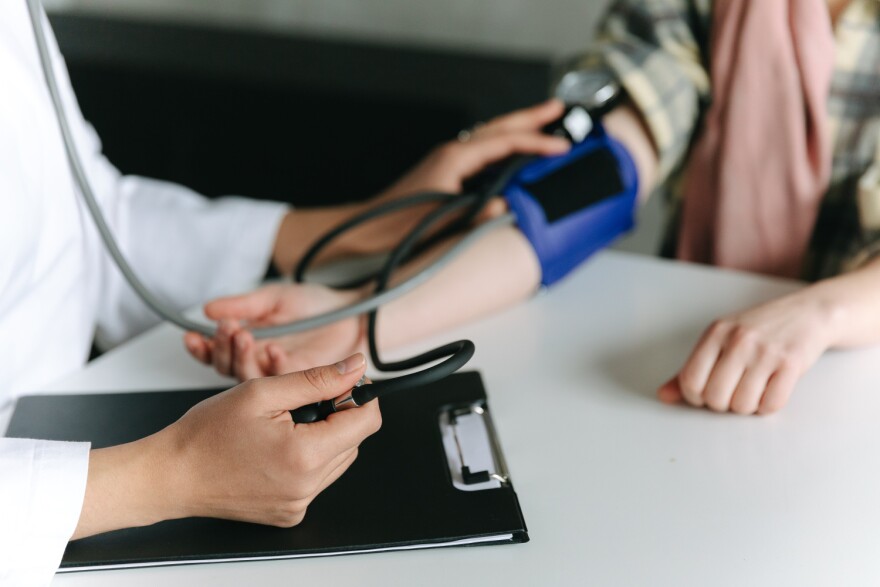 a health care provider takes the blood pressure of a patient while holding a clipboard.