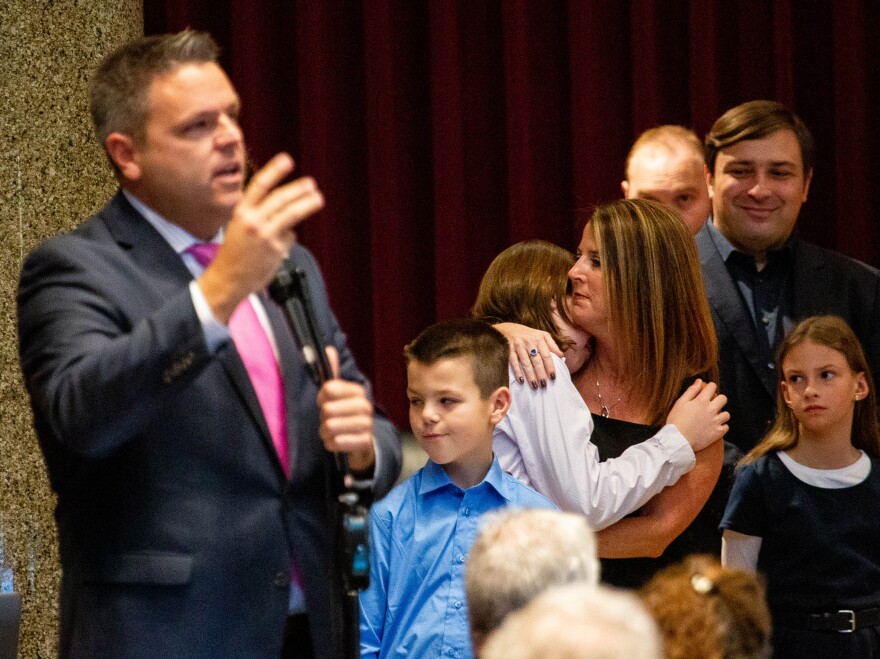 Rep. Justin Hill (R-Lake St. Louis) gives his farewell speech as his wife hugs one of their sons on Wednesday during the first day of the legislative session. 