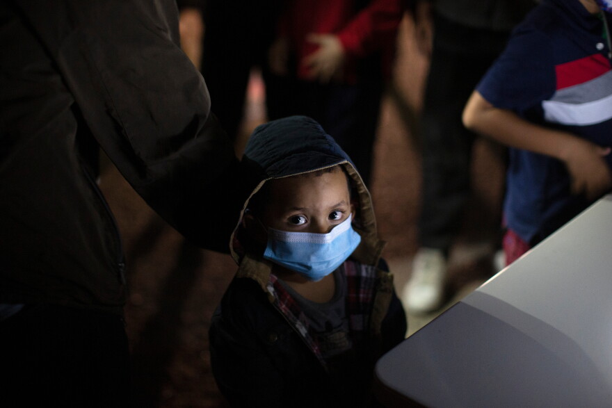 FILE - An unaccompanied minor looks up as he waits to answer questions from a U.S. Border Patrol agent at an intake site after he was smuggled on an inflatable raft across the Rio Grande River, March 24, 2021, in Roma, Texas.
