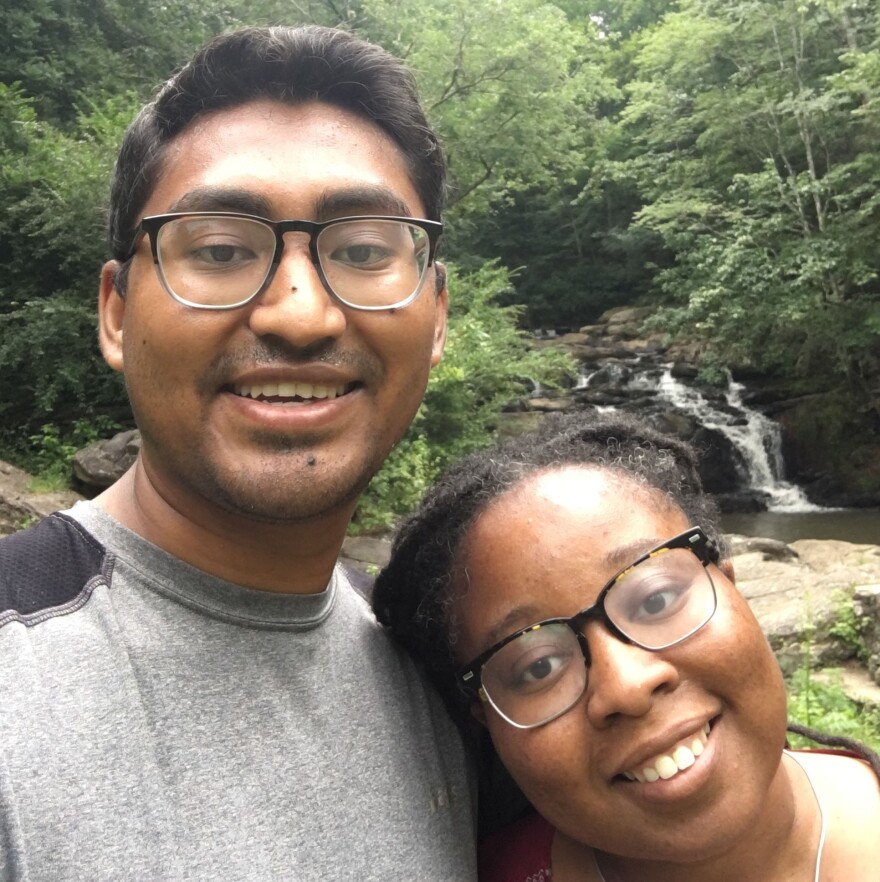 A couple standing in front of trees.