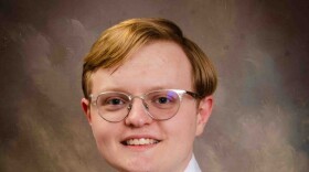 Nicholas Hazelett. A young, red-haired man wearing glasses and dressed in a white dress shirt and blue checkered tie.