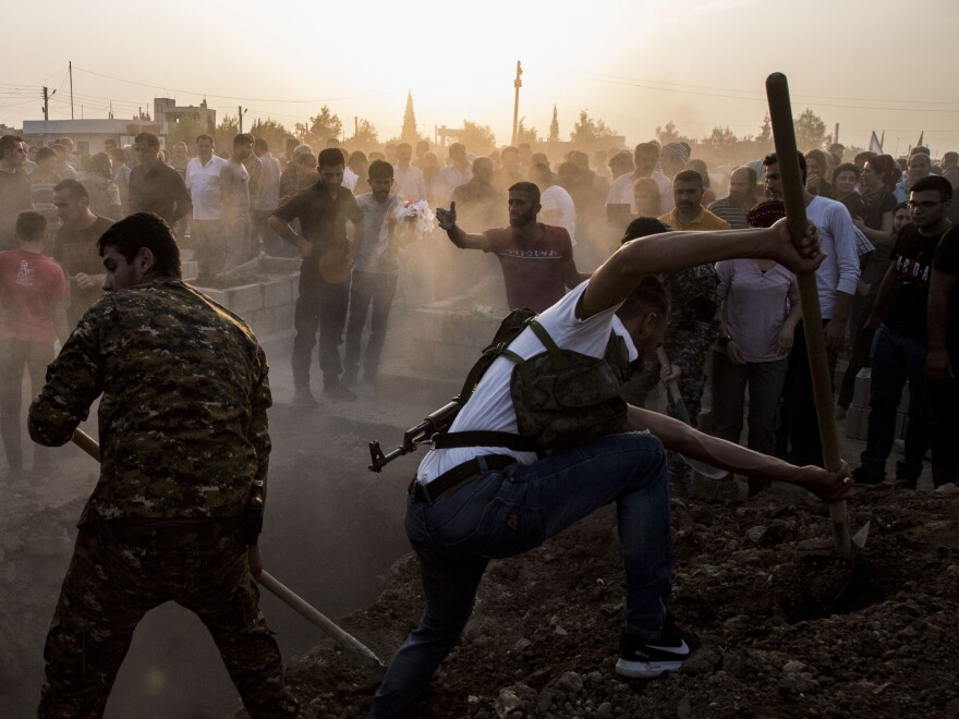 Syrians bury Syrian Democratic Forces fighters killed while battling Turkish forces in the town of Qamishli on Saturday. Turkey's military says it has captured a key Syrian border town as its offensive against Kurdish fighters presses on.