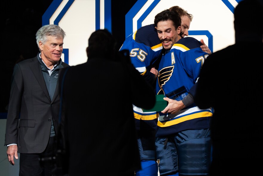 St. Louis Blues defenseman Justin Faulk (72) is embraced by defenseman Colton Parayko (55) while celebrating Faulk’s 1,000th National Hockey League game before a matchup against the Utah Mammoth in the Enterprise Center on Saturday, Nov. 29, 2025 in downtown St. Louis. St. Louis Blues Chairman Tom Stillman stands to the left.