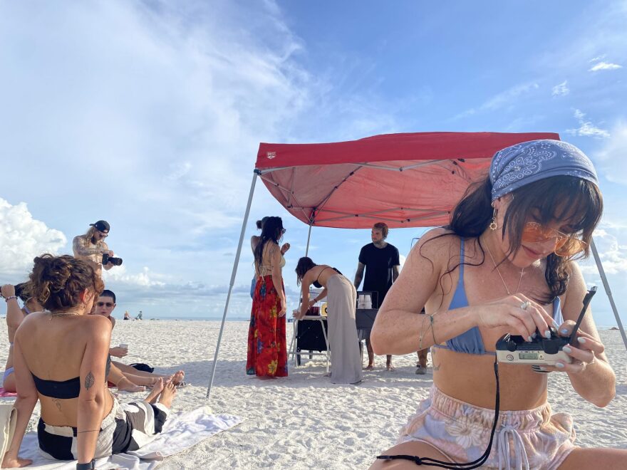 Woman on a beach loading film into a camera