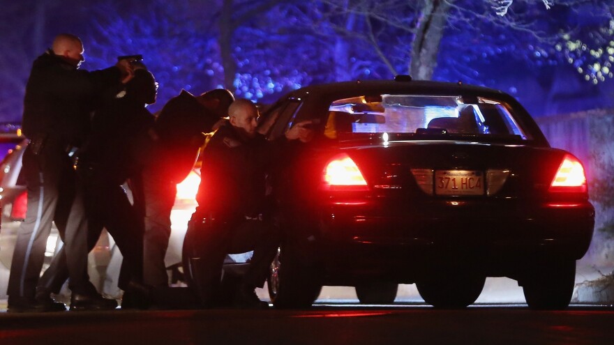 Police with guns drawn search for one of the Boston Marathon suspects early Friday in Watertown, Mass.