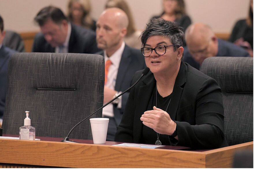 Woman in black jacket sits at a microphone