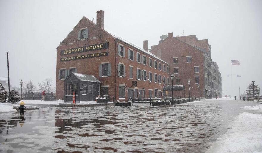 High tide early on Saturday morning during the snow storm creates flooding on Long Wharf by the Chart House in Boston.