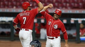 Cincinnati Reds' Eugenio Suarez (7) celebrates hitting a two-run home run with Joey Votto (19) during the eighth inning of an exhibition baseball game against the Detroit Tigers at Great American Ball Park.