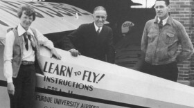 Amelia Earhart, l-r, Purdue University President Edward C. Elliott and Captain L. I. Aretz, standing next to an instructional plane at Purdue Airport, 1936.