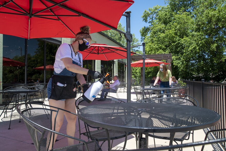 Lauren Howell, a waitress at the Old Herald Brewery and Distillery, sanitizes a table on the restaurants patio. The restaurant will clean tables before and after guests dine at them. 05 29 2020