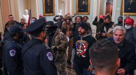 A man wearing a QAnon sweatshirt protests against US Capitol police officers as they try to stop supporters of US President Donald Trump from entering the Capitol in Washington, DC. 