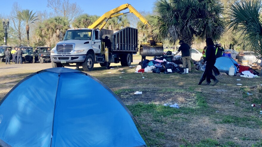 A city excavator moves piles of trash at the LaVilla tent tity Tuesday. 