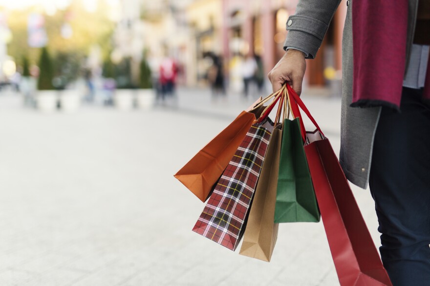 A person holds a bunch of gifts bags in one hand.