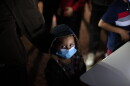 FILE - An unaccompanied minor looks up as he waits to answer questions from a U.S. Border Patrol agent at an intake site after he was smuggled on an inflatable raft across the Rio Grande River, March 24, 2021, in Roma, Texas.