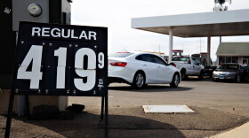 Photo of a gas station with cars lined up at the pumps. In the foreground, a sign shows that regular gas is $4.19 per gallon. 