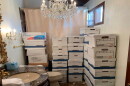 A room with white cardboard boxes filled with documents stacked high.