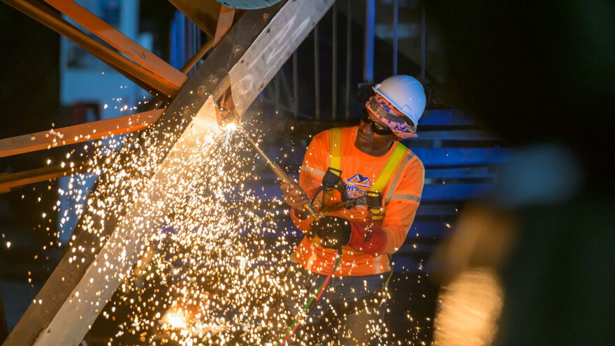 Pictured: A worker with DPW contractor, Rumina Construction, cuts through the steel framework of the former Addelita Cancryn Pedestrian Bridge on St. Thomas during demolition work Friday evening.