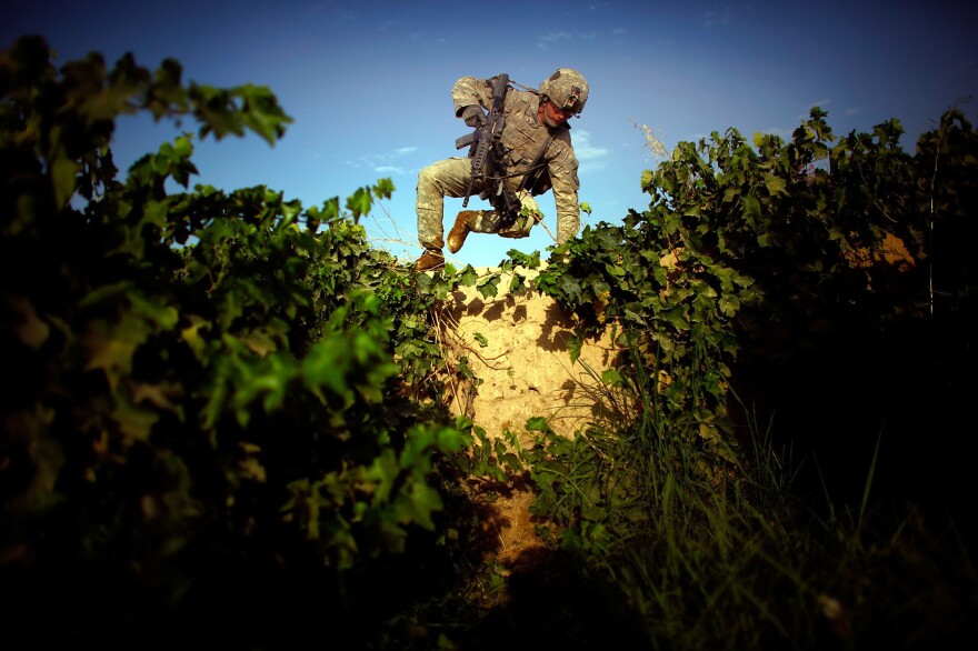 Pfc. James Turner with Bravo Company, 101st Airborne Division jumps over an 8-foot-high mud wall while navigating a grape field and trying to avoid walking on a heavily traveled path in the Pashmul District of Kandahar province in southern Afghanistan.