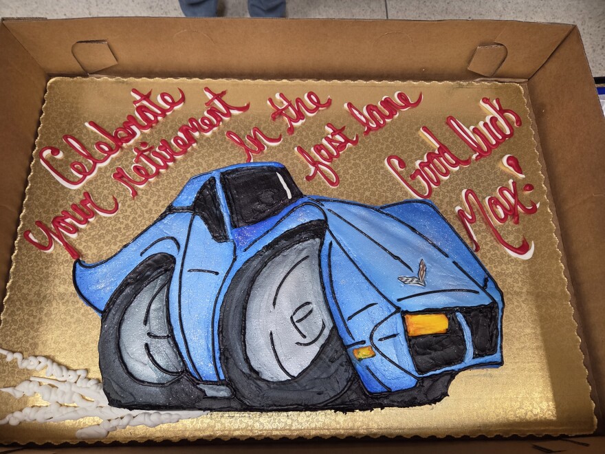 A personalized cake for Max Hites' retirement from Lueken's Village Foods in Bemidji on May 1, 2026. The cake is shaped like a blue Corvette. The frosting on the cake's tray reads "Celebrate your retirement in the fast lane! Good luck Max!"