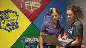 Dr. Justine Bunka and medical assistant Jordann McNees on the first day of seeing patients at Kalamazoo Pediatrics in Portage are standing in the Harry Potter examining room. Dr. Bunka is in blue scrubs. McNees is in a green branded athletic style medical attire.