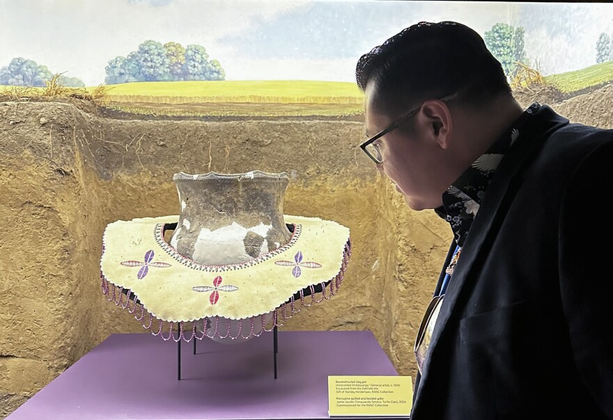 Jamie Jacobs, whose traditional name in Seneca is Hoya’danä:gwa’d, looks at an 1100-year-old clay pot draped in an artwork he created as a symbol of sacred femininity.