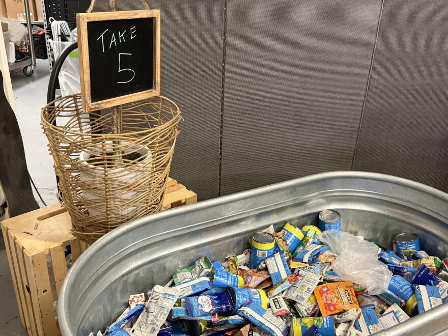 A tub filled with different food items, with a sign that lets visitors know how many they can grab.
