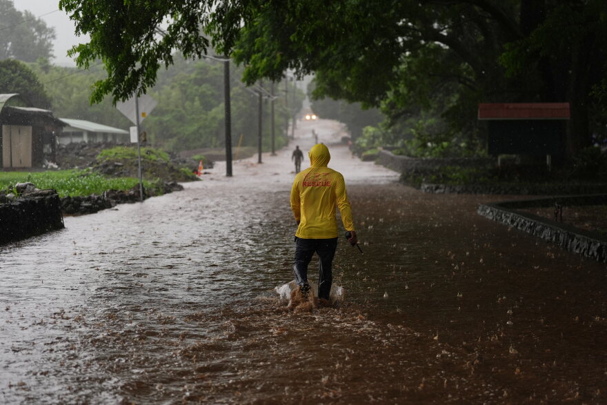 Fire Captain Lui Sales of the Hawaii Fire Department looks for residents to help as rainwater from nearby Hurricane Nolo flood a section of Mamalahoa highway Saturday, Sept. 26, 2026, near Naalehu, Hawaii. (AP Photo/Gregory Bull)