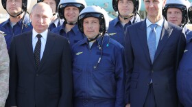 Russian President Vladimir Putin, left, and Syrian President Bashar Assad, right, pose for a photo with Russian military pilots at the Hemeimeem air base in Syria last December.
