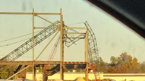 Shot from inside a car: a photo of a construction crane that has fallen over recent construction beams and broken into pieces.