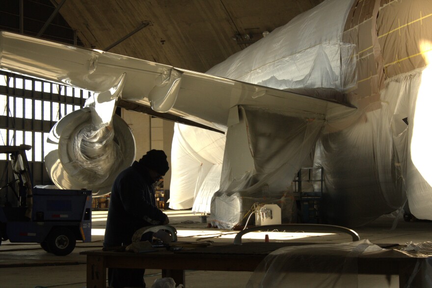 Aircraft maintenance company Aero Intelligence is using Loring's historic Arch Hangar to retrofit jumbo jets. Here, a worker helps prepare a former Air New Zealand Boeing 777 for its next owner on Nov. 19, 2025.
