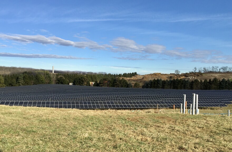 An array of solar panels in a field against a blue sky